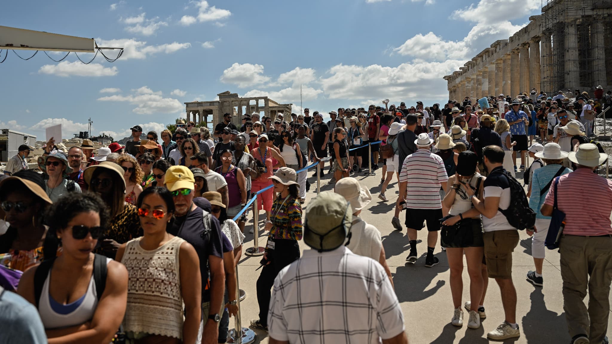 Des touristes font la queue aux Propylaia, l'ancienne porte du monument, lors de leur visite de l'Acropole à Athènes, le 14 juin 2023.