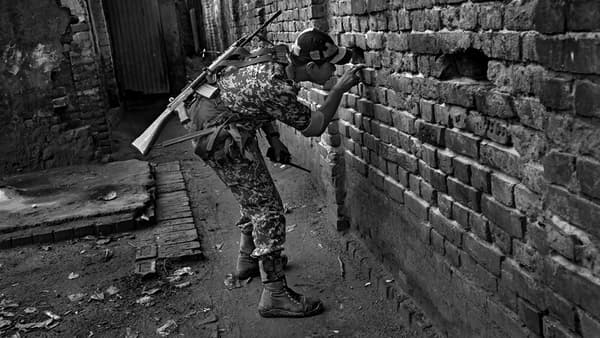 Un soldat profite d'un trou dans le mur pour observer les mouvements de Bangladais qui s'approcheraient du mur pour le franchir ou recevoir des produits indiens par une autre ouverture.