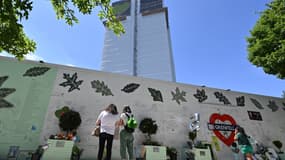 Des personnes se rassemblent devant le mémorial de fortune créé sur le mur entourant la tour Grenfell dans l'ouest de Londres, le 14 juin 2022, à l'occasion du cinquième anniversaire de la tragédie, afin de rendre hommage aux victimes.