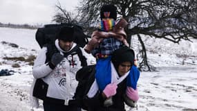 Une famille de réfugiés marche dans un champs enneigés après avoir traversé la frontière entre la Macédoine et la Serbie. 