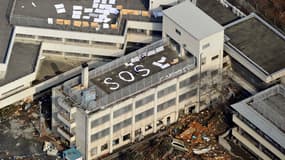 A Kesennuma, au nord de Sendai, des gens lancent un SOS pour être secourus sur le toit d’un immeuble.