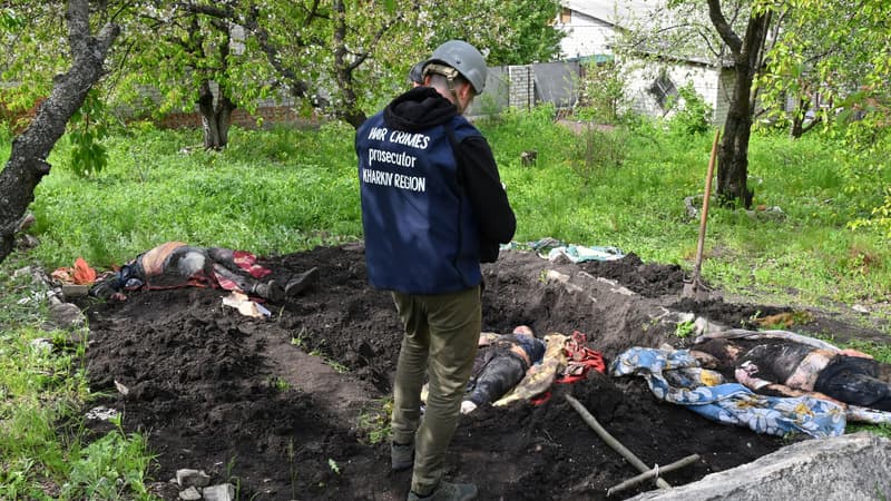 Un homme se tient devant les corps exhumés de civils d'une habitation du village de Stepanky, près de Kharkiv, en Ukraine, le 11 mai 2022