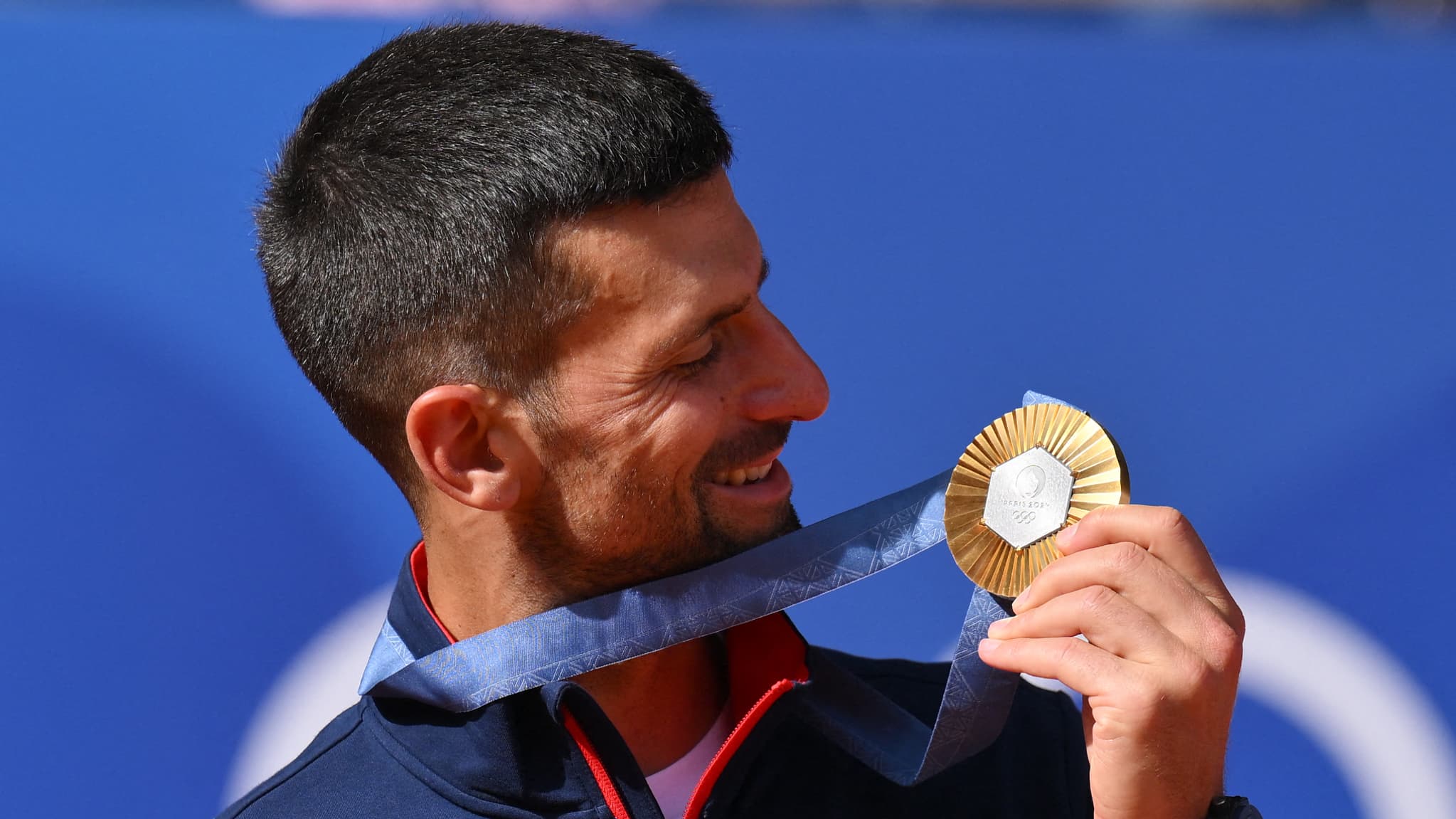 Novak Djokovic regarde sa médaille d'or remportée au tennis