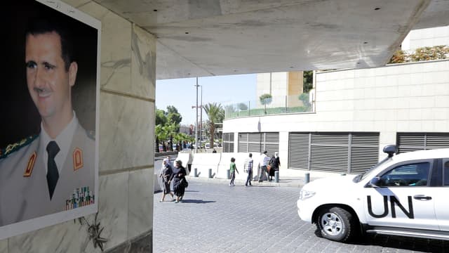 Un véhicule des Nations unies transportant des inspecteurs de l'OIAC passe devant un portrait de Bachar al-Assad, le 9 octobre 2013, à Damas.