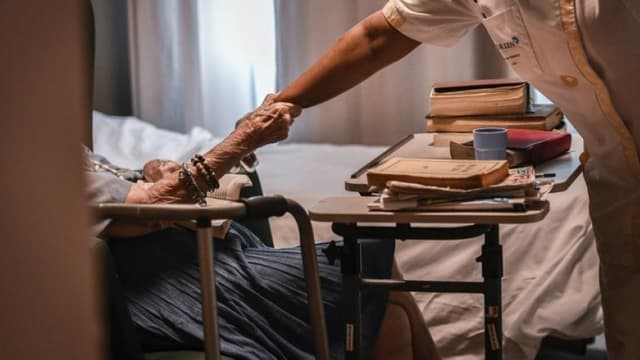 Image d'illustration - Une personne âgée tenant le bras d'une aide-soignante dans un établissement EHPAD parisien