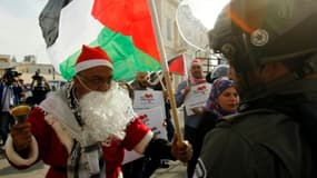 Un manifestant palestinien habillé en père Noël s'oppose à un membre des forces de l'ordre israélienne à Bethléem, en Cisjordanie occupée, le 23 décembre 2017