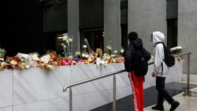 Des adolescents se recueillent devant les bouquets de fleurs exposés à l'entrée de l'immeuble où habitait Lola, une lycéenne de 12 ans retrouvée morte dans un coffre dans le 19e arrondissement, à Paris le 17 octobre 2022