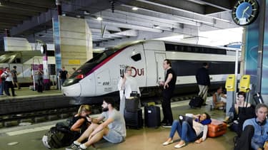 Des voyageurs attendent sur un quai de la gare Montparnasse le 27 juillet 2018, à Paris.