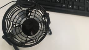 Un mini ventilateur de table, posé près d'un ordinateur.