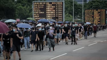 Des manifestants brandissant des parapluies près de l'aéroport.