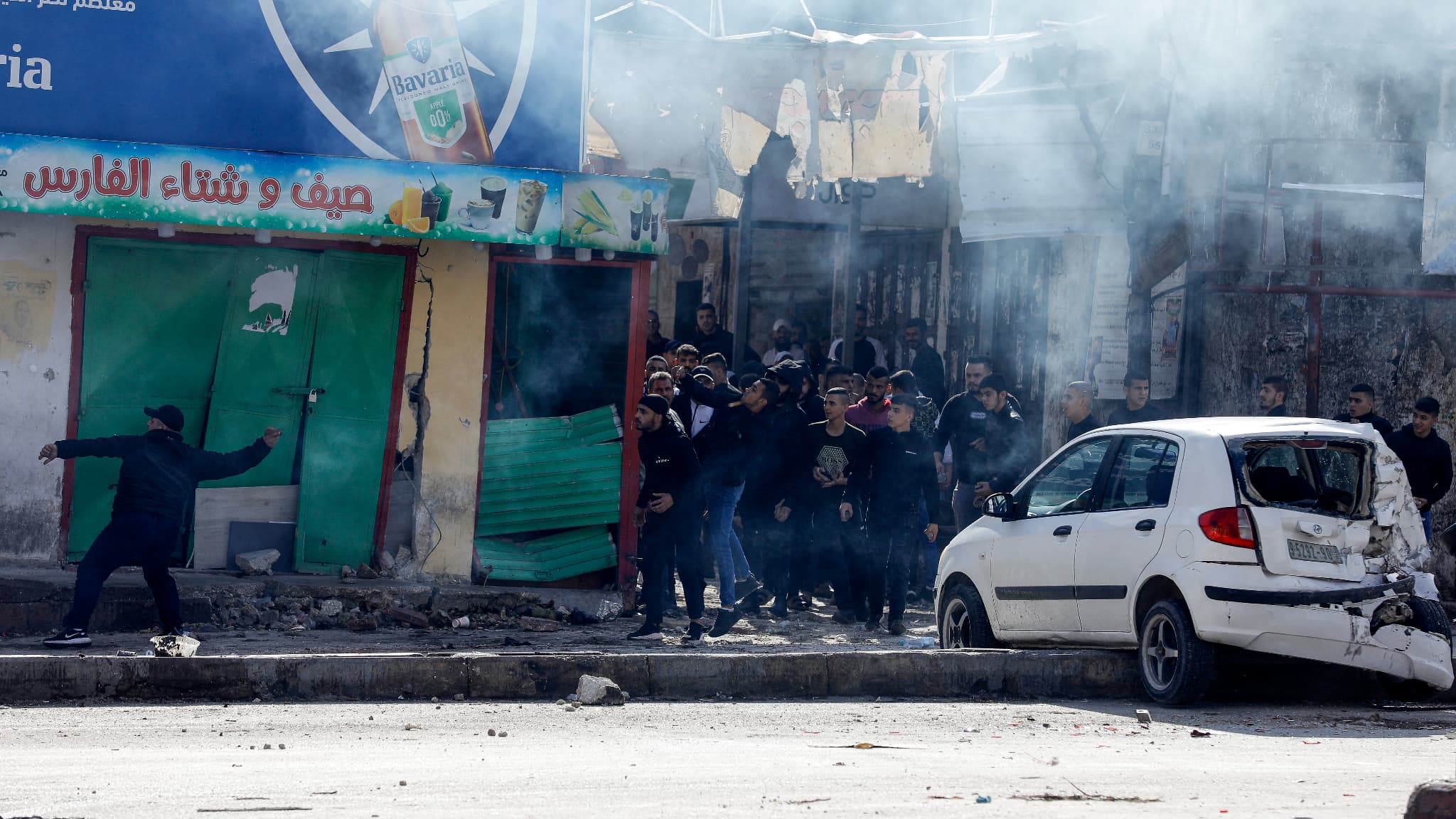 Des jeunes palestiniens lancent des pierres sur des véhicules de l'armée israélienne après un raid dans le camp de réfugiés de Balata, à l'est de la ville de Naplouse, en Cisjordanie, le 21 novembre 2023.