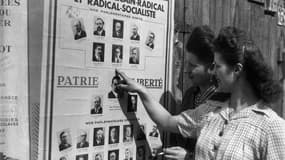 Des femmes regardent un panneau électoral avant d'aller voter pour la première fois lors du premier tour des élections municipales, le 29 avril 1945.