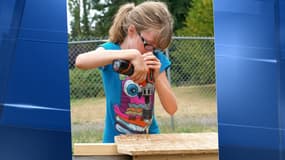 Hailey en train de fabriquer un abri en bois, avec sa perceuse.