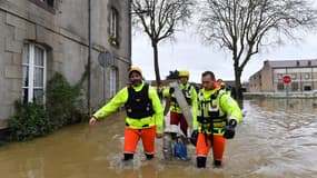 Des secouristes transportent des pompes pour accélérer la baisse du niveau de l'eau, dans une rue inondée de Saint-Nicolas-de-Redon, en Ille-et-Vilaine, le 1er février 2025.