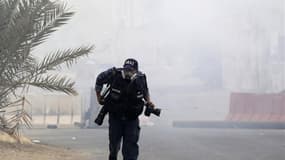 Un photographe se mettant à couvert lors d'affrontements au Bahreïn. L'année 2012 a été la plus meurtrière pour les journalistes depuis 1995 et le premier bilan annuel de Reporters sans frontières. /Photo prise le 24 mars 2012/REUTERS/Ahmed Jadallah