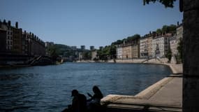 Des personnes assises à l'ombre sur les quais, le 18 juin 2022 à Lyon, lors d'une vague de chaleur