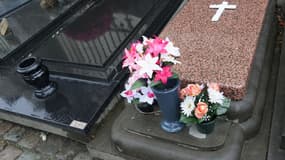Quelques pots vides et des fleurs en plastique sur des tombes dans un cimetière catholique.