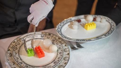 Un majordome s'exerce à servir des mets avec des jouets en plastique dans une école hôtelière à Chengdu (Chine) le 23 mars 2015