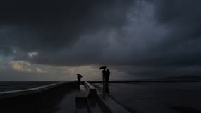 Des personnes se tiennent sous des parapluies pendant une forte pluie à Nice sur la Côte d'Azur, le 3 mars 2024.