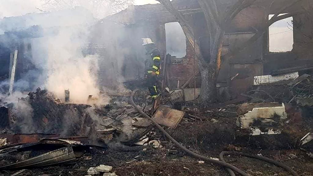 Cette photo prise et publiée par le service d'urgence de l'État ukrainien le 25 mars 2022 montre un pompier en train d'éteindre un incendie après un bombardement russe à Kharkiv.
