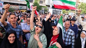 Des Iraniens brandissent des drapeaux et des pancartes lors d'un rassemblement de protestation contre l'attaque américaine contre l'Iran sur la place Enghelab à Téhéran, le 22 juin 2025. 