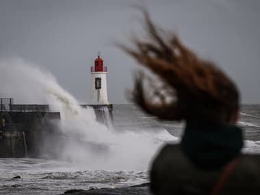 Une femme regarde les vagues s'écraser contre le phare à l'entrée du port pendant la tempête Nelson, aux Sables-d'Olonne, dans l'ouest de la France, le 28 mars 2024.