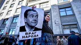 Une manifestante tenant un portrait de Dmitri Medvedev avec l'inscription "Ennemi du peuple".