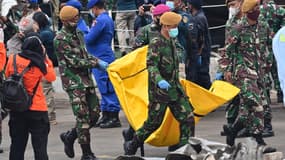 Des soldats indonésiens transportent des objets récupérés sur le vol SJ182 de Sriwijaya Air au port de Tanjung Priok, au nord de Jakarta, le 12 janvier 2021.