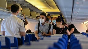Des passagers, portant des masques, embarquent à l'aéroport international de Pudong à Shanghai pour un vol à destination de Wuhan, le 14 juillet 2020 
