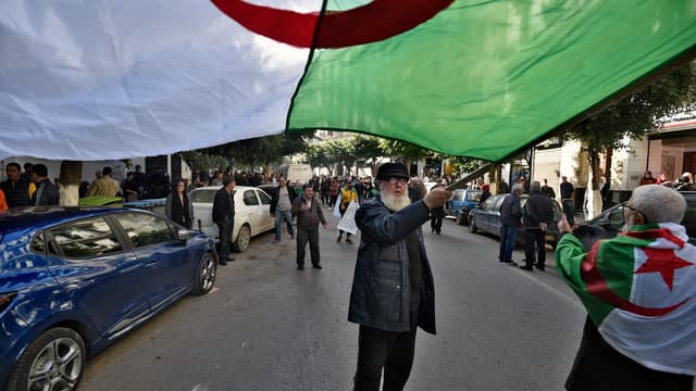 Un homme agitant le drapeau algérien.