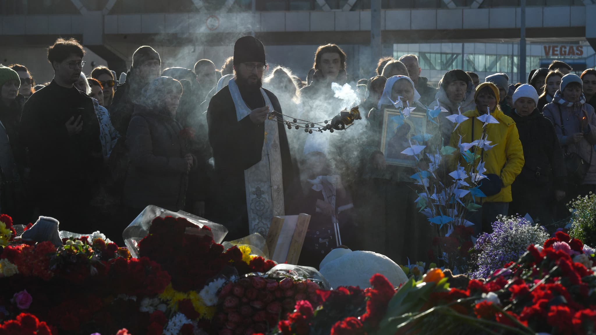 Un prêtre orthodoxe dirige une messe devant le Crocus City Hall en hommage aux victimes de l'attentat près de Moscou, le 25 mars 2024