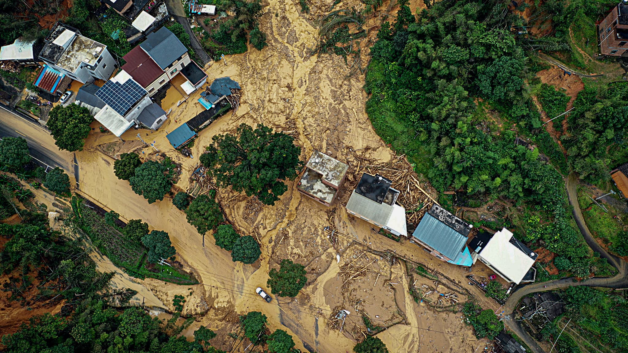 Cette photo montre une vue aérienne d'une voiture passant à côté d'un site de glissement de terrain après des tempêtes à Longyan, dans la province de Fujian, dans l'est de la Chine, le 17 juin 2024.