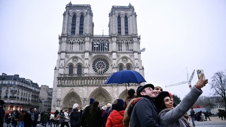 Des personnes prennent un selfie devant Notre-Dame de Paris, le 24 décembre 2024
