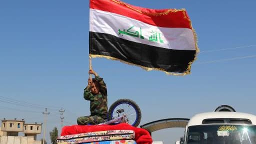 Un enfant irakien brandit le drapeau national alors que des familles déplacées quittent Kirkuk pour retourner à Tikrit, Samara et al-Alam, le 2 avril 2015
