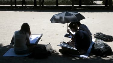 Des jeunes gens se rafraîchissent à l'ombre dans l'enceinte du Palais Royal à Paris, le 6 juillet 2015.
