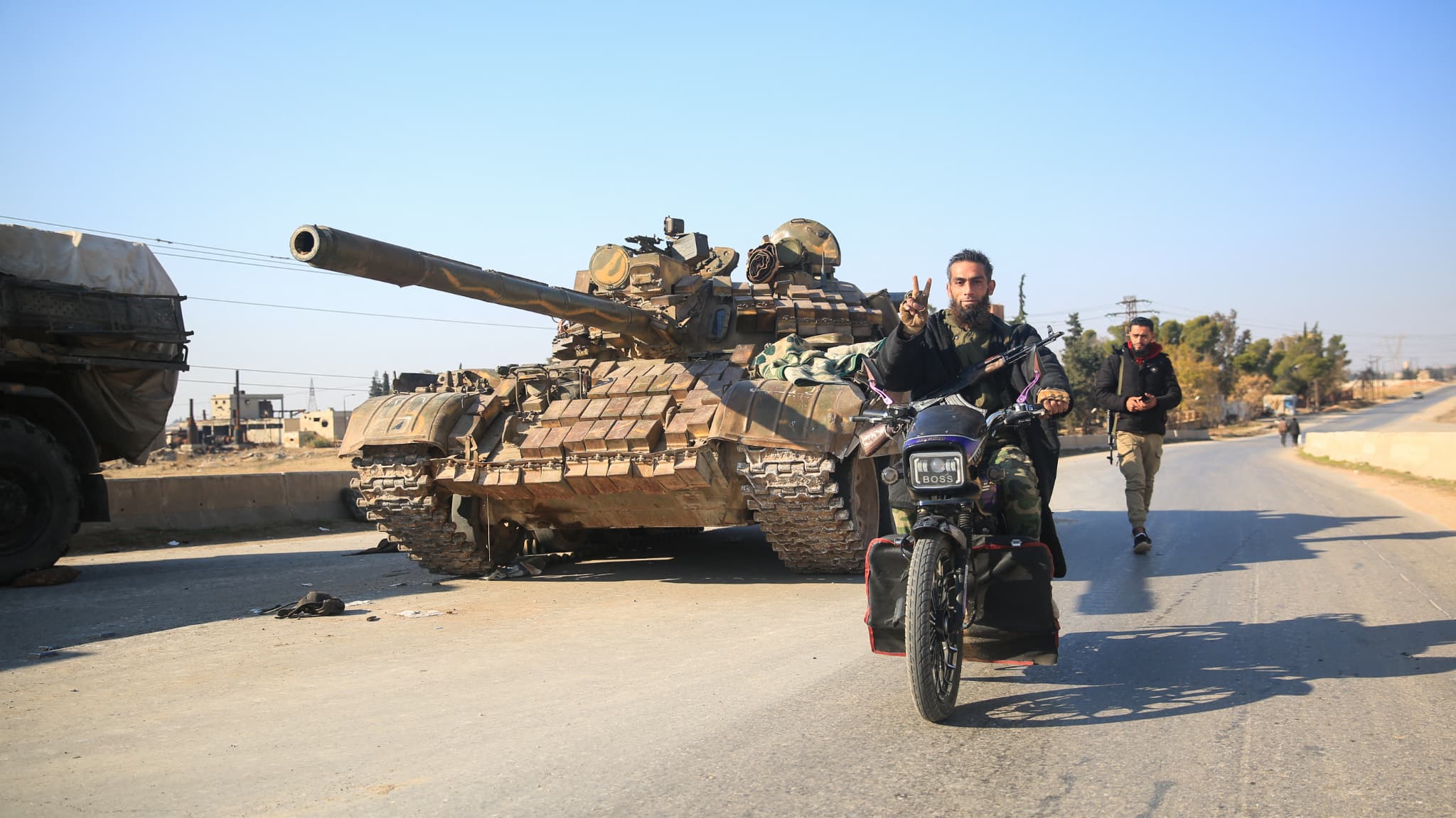 Des combattants anti-gouvernementaux passent devant des équipements et des véhicules militaires abandonnés de l'armée syrienne, alors qu'ils atteignent la ville d'al-Safirah au sud-est de la ville d'Alep en Syrie, le 3 décembre 2024.