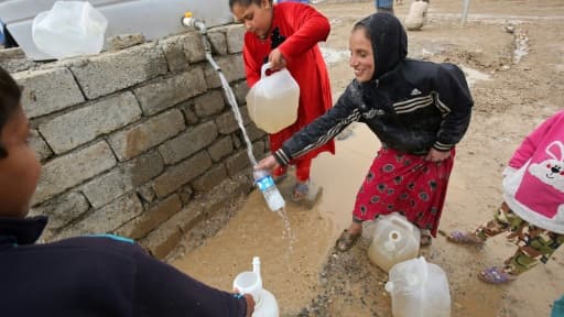 Des enfants remplissent d'eau des jerricans dans le camp de Hammam al-Alil, le 18 mars 2017 en Irak