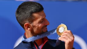 Novak Djokovic regarde sa médaille d'or remportée au tennis