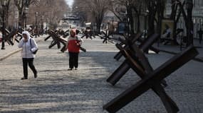 Des personnes passent devant des obstacles antichars dans le centre-ville d'Odessa, le 5 avril 2022.
