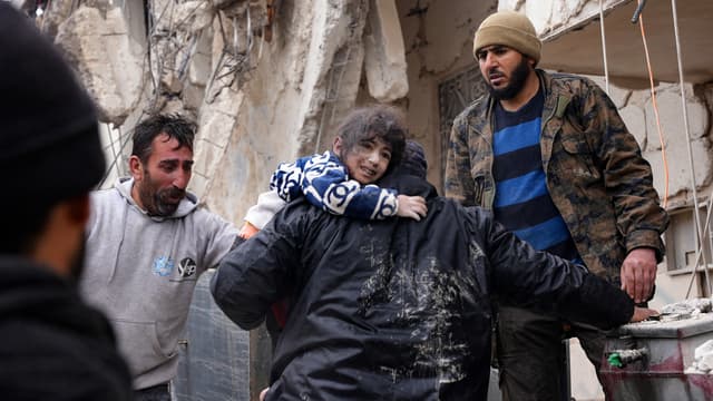 Des habitants récupèrent un enfant dans les décombres d'un bâtiment effondré suite à un tremblement de terre dans la ville de Jandaris, dans la campagne de la ville d'Afrin, au nord-ouest de la Syrie, dans la partie de la province d'Alep tenue par les rebelles, le 6 février 2023.