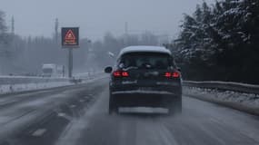 Une voiture roule sous la neige, avec un panneau mettant en garde contre le verglas, sur l'A6, à Vimy, dans le Pas-de-Calais, le 9 janvier 2025