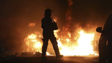 Un policier près d'un véhicule en feu à La Réunion ce lundi, lors des violences survenues en marge des gilets jaunes.
.