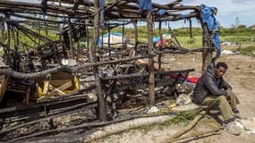 Un migrant assis près de son logement incendié, le 1er juin 2015 à Calais