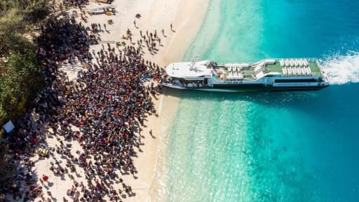 Vue aérienne d'une foule attendant de quitter l'île indonésienne de Gili Trawangan, voisine de celle de Lombok, frappée dimanche par un séisme meurtrier, le 8 août 2018 Vue aérienne d'une foule attendant de quitter l'île indonésienne de Gili Trawangan, voisine de celle de Lombok, frappée dimanche par un séisme meurtrier, le 8 août 2018