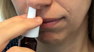 Une femme en train de mettre du spray nasal.