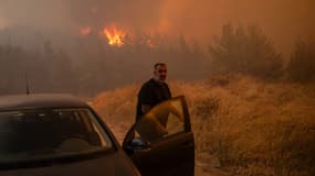 Un habitant montant dans sa voiture alors qu'un incendie fait rage dans le village de Dion, en Grèce, ce lundi 12 août 2024.