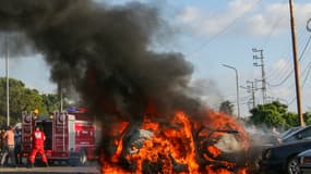 Des pompiers arrivent alors qu'une voiture brûle suite à une frappe israélienne dans la ville de Sidon, au sud du Liban, le 9 août 2024.