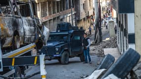 Un policier monte la garde dans une rue d'Ankara, jonchée par des véhicules détruits. 