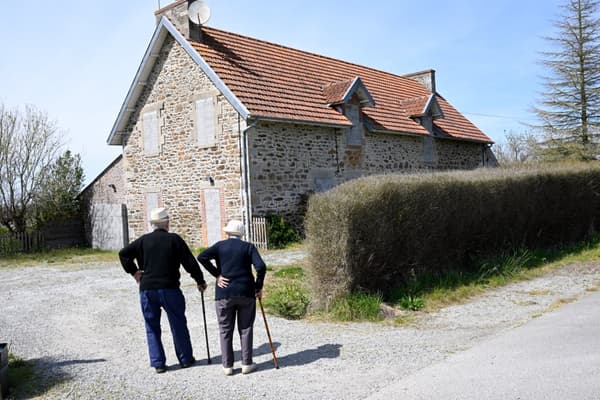 Deux personnes devant une maison condamnée par la future montée des eaux, près d'une digue à Lancieux, dans l'ouest de la France, le 5 mai 2022.