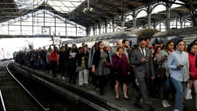 Des voyageurs marchent le 24 avril 2018 sur un quai en quittant un RER à la gare Saint-Lazare à Paris, alors que les cheminots français poursuivent une deuxième journée de grève en raison des réformes prévues pour remanier la compagnie ferroviaire nationale publique SNCF